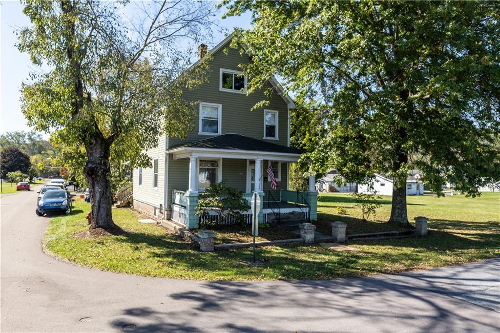 a front view of a house with a yard tree and outdoor seating