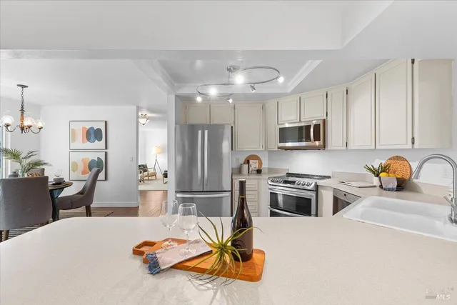 a kitchen with stainless steel appliances granite countertop a refrigerator a stove top oven a sink dishwasher and white cabinets with wooden floor