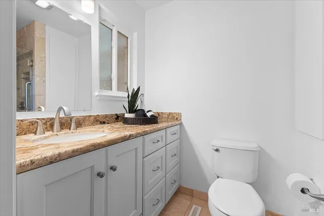a bathroom with a granite countertop toilet sink and mirror