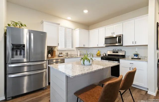 a kitchen with a refrigerator a stove a sink and white cabinets