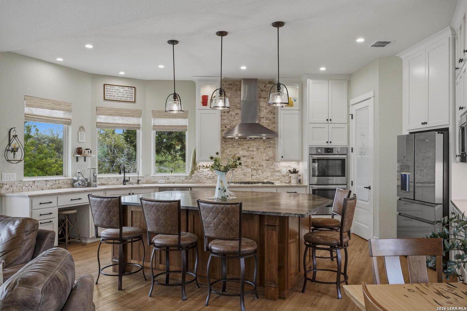 134 Stallion Estates Drive Spring Branch, TX 78070 - Photo 13 of 67 a kitchen with stainless steel appliances kitchen island granite countertop a dining table chairs and white cabinets