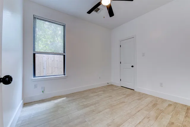 a view of an empty room with a window and wooden floor
