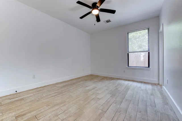 a view of empty room with wooden floor and fan