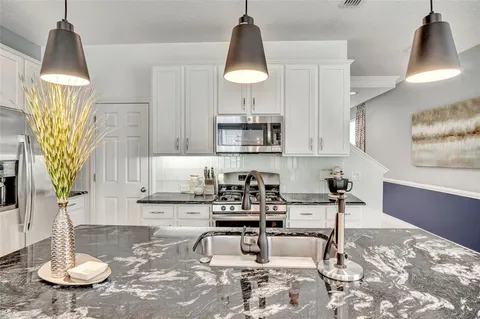 a kitchen with stainless steel appliances a sink a table and chairs in it
