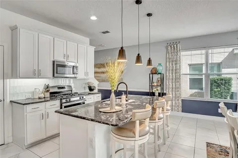 a kitchen with kitchen island granite countertop a sink a stove a oven a dining table and chairs