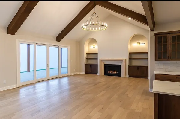 a view of an empty room with wooden floor fireplace and a window