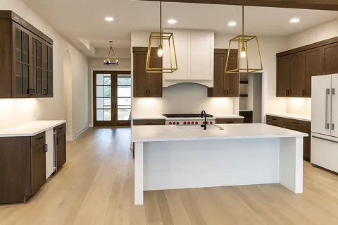 a large kitchen with stainless steel appliances a large counter top a refrigerator a stove a sink and a oven