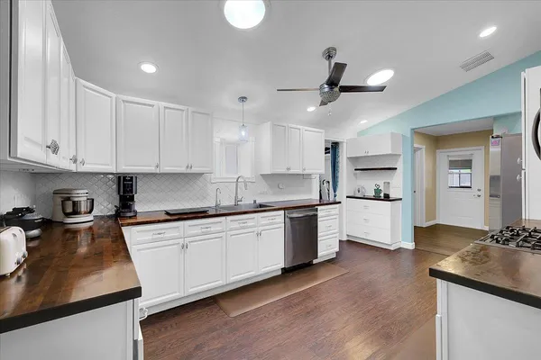 a kitchen with white cabinets stainless steel appliances and wooden floor