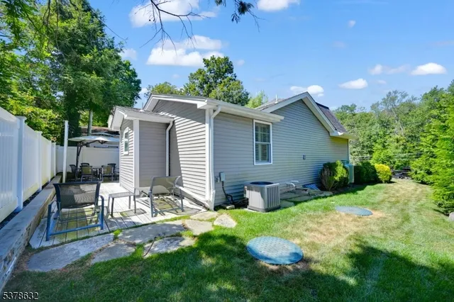 a view of a backyard with table and chairs potted plants and a large tree