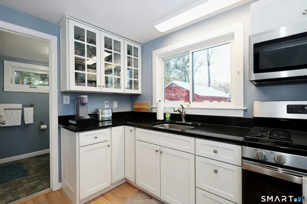 a kitchen with granite countertop a sink a stove and cabinets