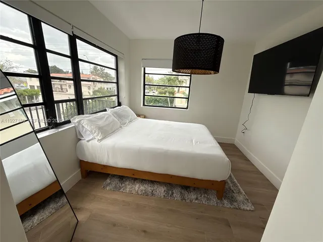 a bedroom with a bed a dresser and a flat screen tv