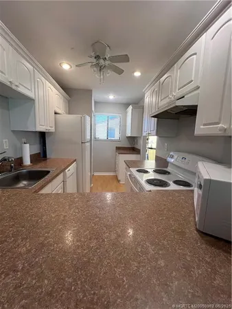 a kitchen with stainless steel appliances granite countertop a sink refrigerator and cabinets