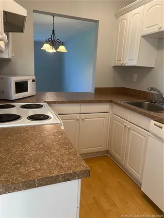 a kitchen with granite countertop white cabinets and white appliances