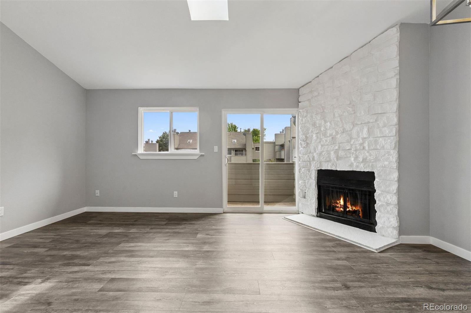 3100 South Federal Boulevard, Unit 331 Denver, CO 80236 - Photo 25 of 29 a view of an empty room with wooden floor and a fireplace