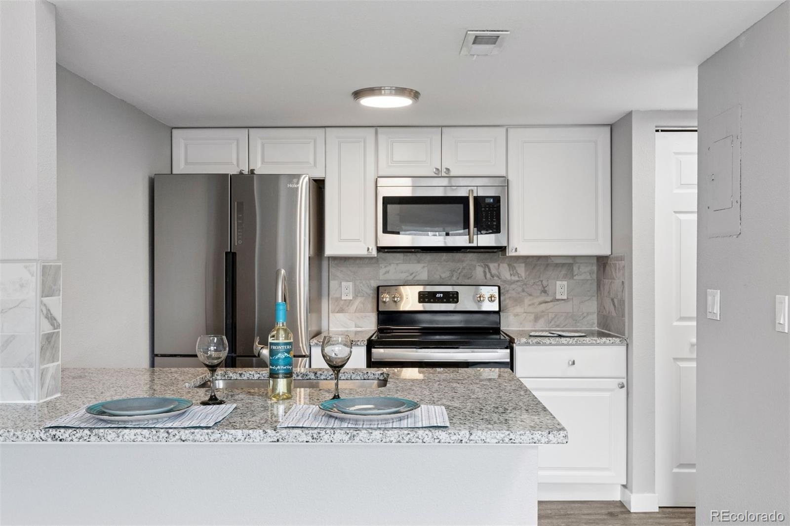3100 South Federal Boulevard, Unit 331 Denver, CO 80236 - Photo 5 of 29 a kitchen with kitchen island a counter top space cabinets and stainless steel appliances
