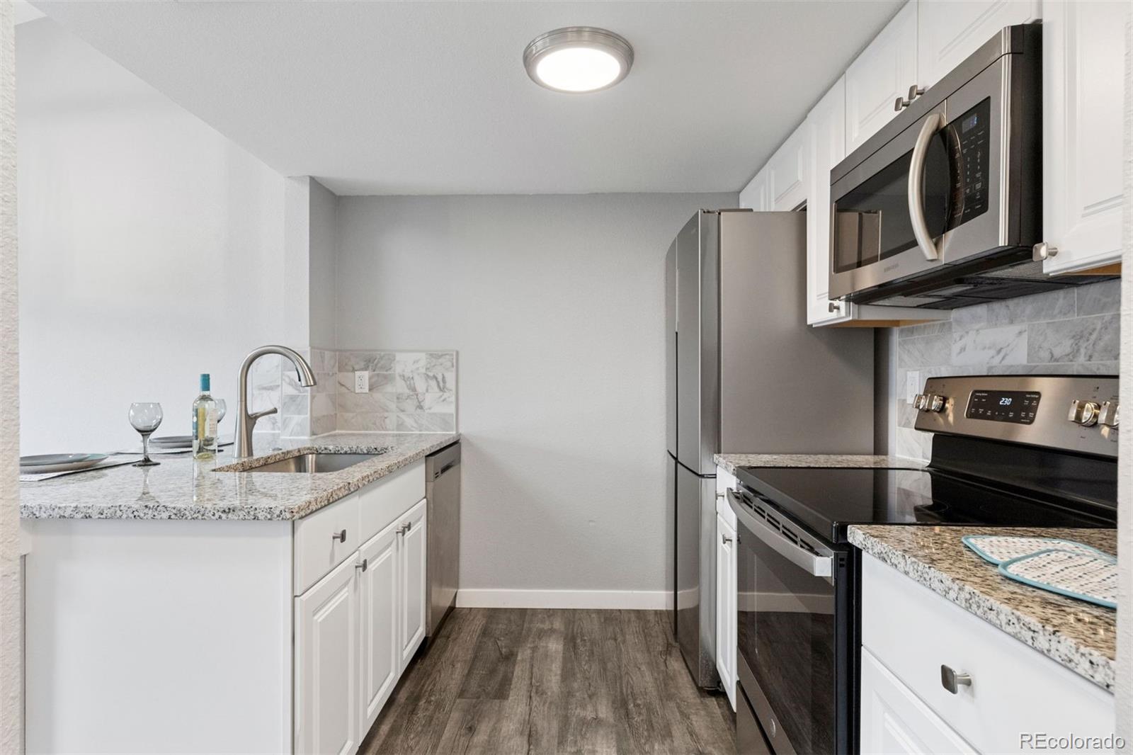 3100 South Federal Boulevard, Unit 331 Denver, CO 80236 - Photo 6 of 29 a kitchen with stainless steel appliances granite countertop a sink stove and microwave
