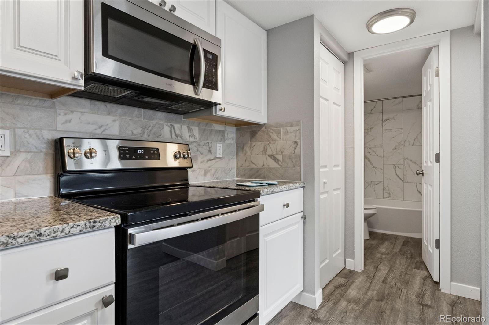 3100 South Federal Boulevard, Unit 331 Denver, CO 80236 - Photo 7 of 29 a kitchen with stainless steel appliances a stove a microwave and cabinets