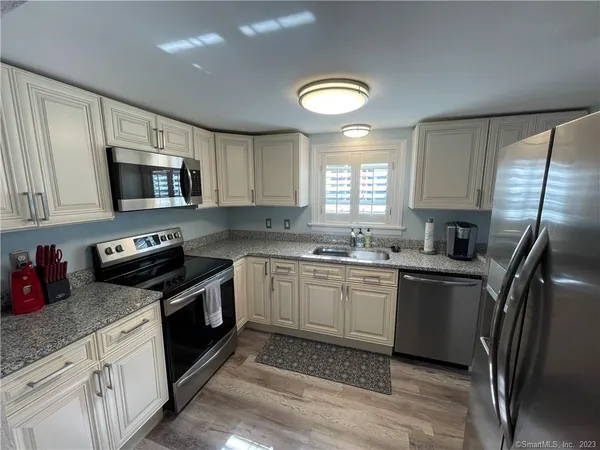 a kitchen with stainless steel appliances granite countertop a stove sink microwave and window