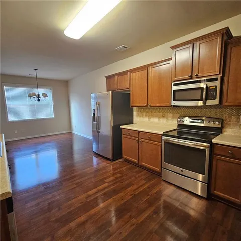 a kitchen with granite countertop wooden floors stainless steel appliances and cabinets