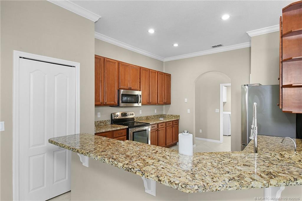 439 Northwest Sunflower Place Stuart, FL 34994 - Photo 8 of 68 a kitchen with stainless steel appliances granite countertop a sink stove and refrigerator