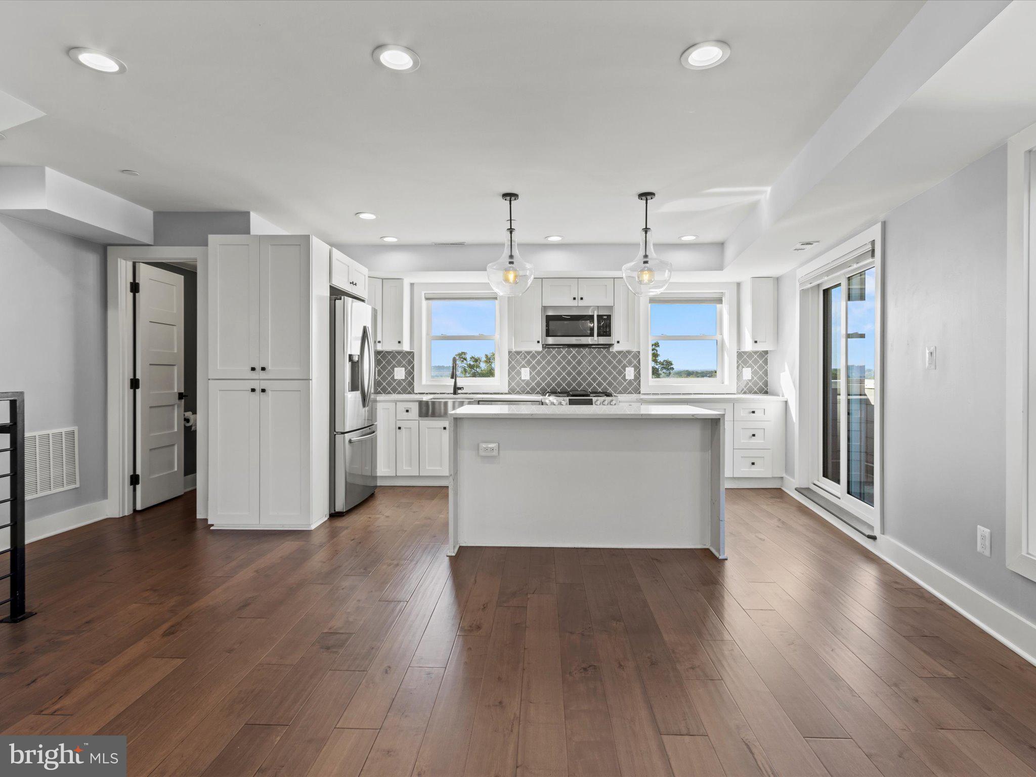1267 Penn Street Northeast, Unit B Washington, DC 20002 - Photo 4 of 20 a large kitchen with stainless steel appliances a refrigerator and wooden floor