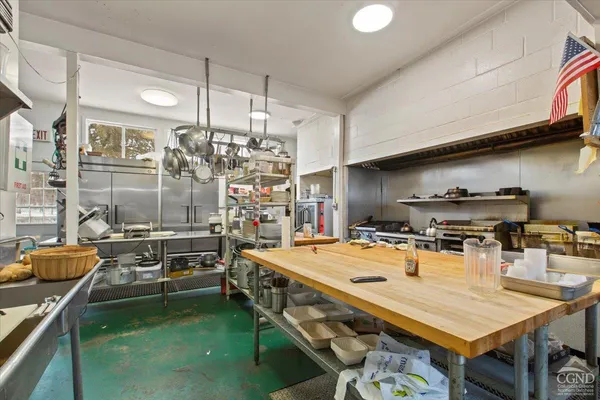 a kitchen with stainless steel appliances granite countertop a stove a refrigerator a sink a dining table and chairs with wooden floor