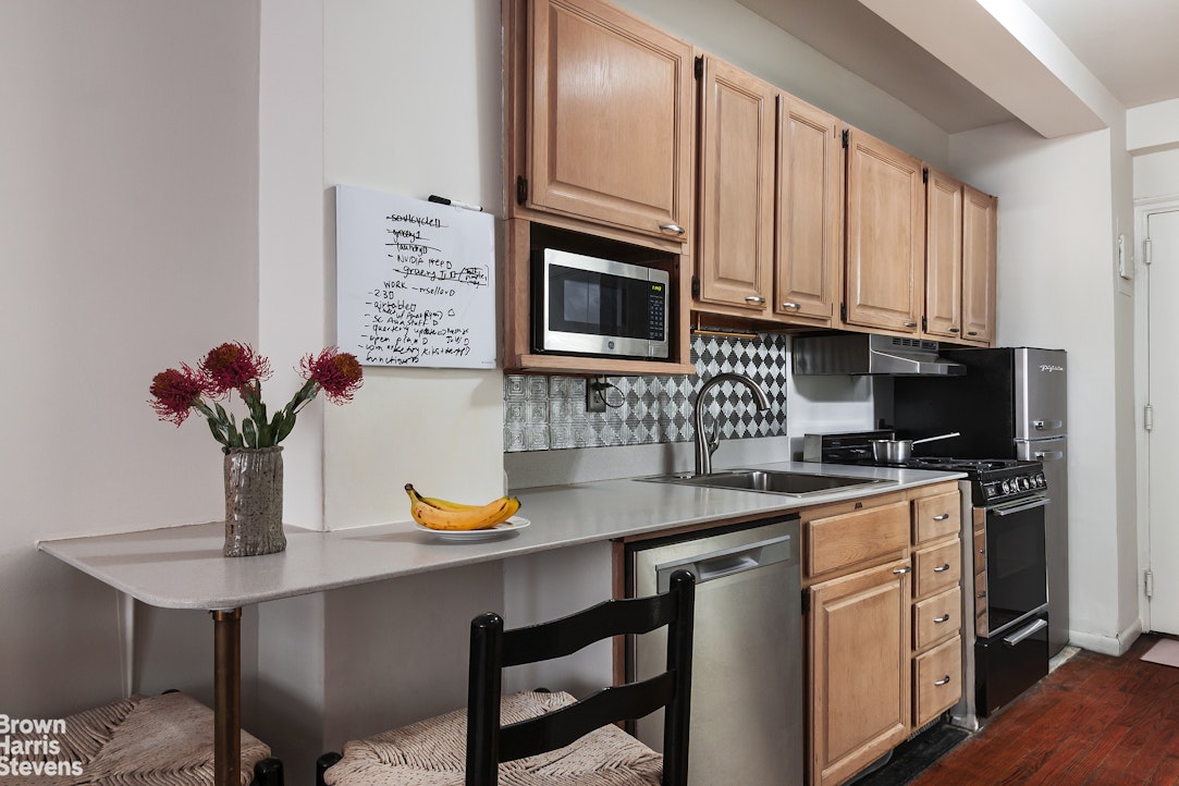 433 West 34th Street, Unit 5M Manhattan, NY 10001 - Photo 4 of 13 a kitchen with stainless steel appliances granite countertop a sink a stove and a microwave