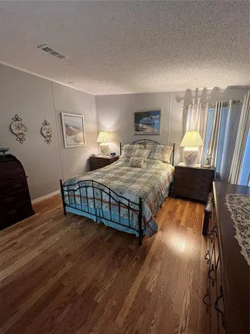 a bedroom with a bed next to a large window with dresser