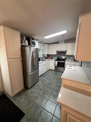 a kitchen with kitchen island a counter top space a sink a refrigerator and a stove