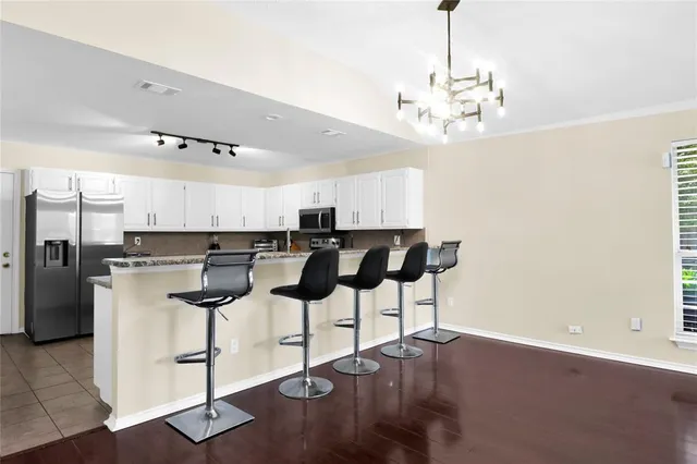 a kitchen with a chandelier stainless steel appliances a dining table chairs and a chandelier