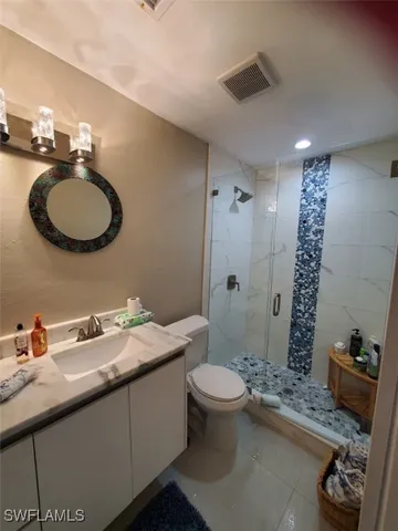 a bathroom with a granite countertop sink mirror vanity and toilet
