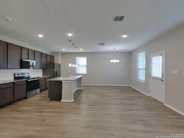 a large kitchen with stainless steel appliances granite countertop a large counter top a stove a sink and a refrigerator