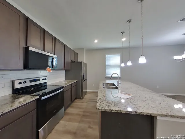 a kitchen with stainless steel appliances granite countertop a sink a stove top oven a granite counter space and cabinets