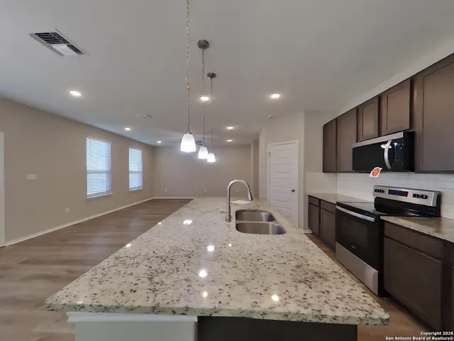 a kitchen with stainless steel appliances granite countertop a sink a stove and a refrigerator