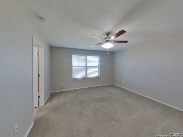 an empty room with a window and a fan