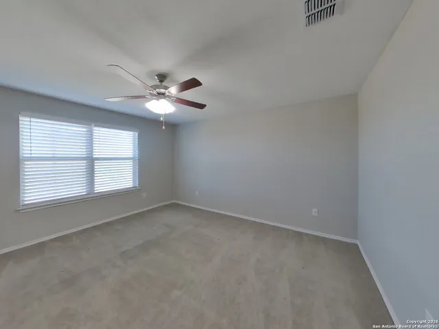 an empty room with a window and a ceiling fan