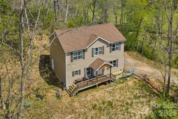 an aerial view of a house with yard and trees in the background