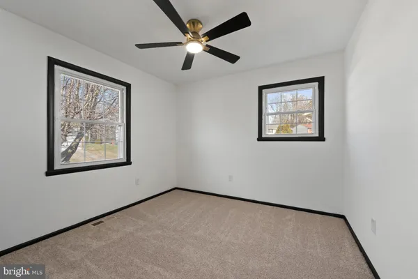an empty room with windows and fan