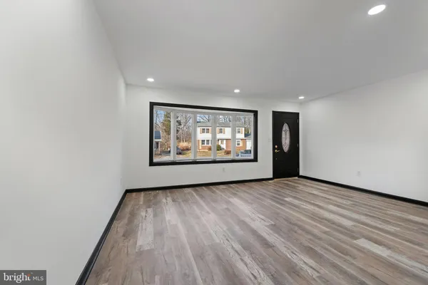 a view of an empty room with wooden floor and window