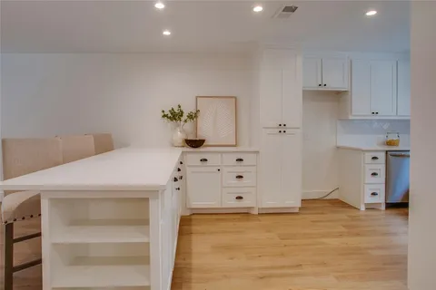 a view of a kitchen with white cabinets and wooden floor