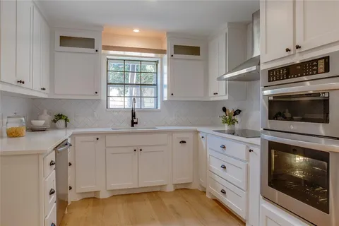 a kitchen with white cabinets and sink