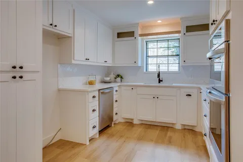 a view of cabinets with stainless steel appliances kitchen island sink and living room