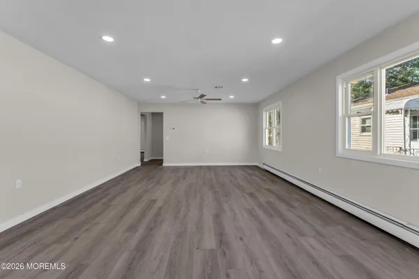 an empty room with wooden floor and windows
