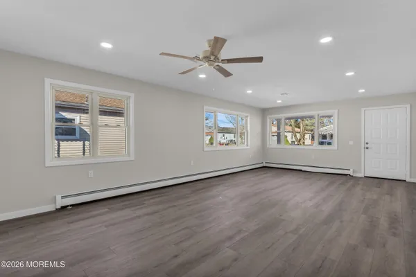 a view of an empty room with a window and wooden floor
