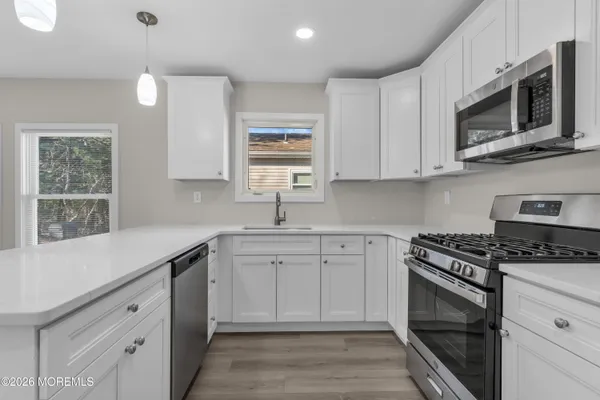 a kitchen with stainless steel appliances granite countertop a sink dishwasher a stove and a microwave oven with cabinets