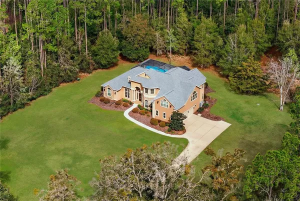 a view of a house with a big yard and large trees
