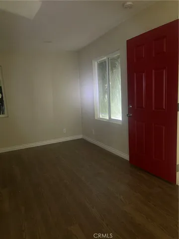 an empty room with wooden floor and windows with curtains
