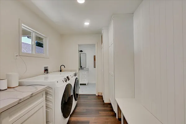 a kitchen with granite countertop a refrigerator a sink dishwasher and white cabinets with wooden floor