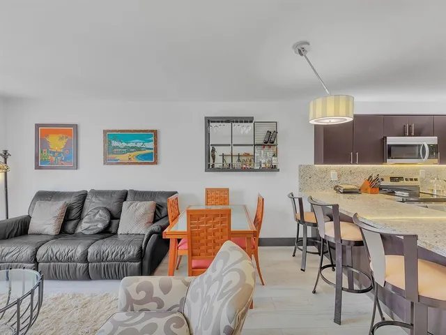 a living room with furniture a flat screen tv and kitchen view