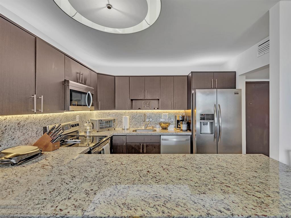 1421 South Ocean Boulevard, Unit 506 Pompano Beach, FL 33062 - Photo 17 of 36 a large kitchen with stainless steel appliances kitchen island granite countertop a refrigerator and a sink